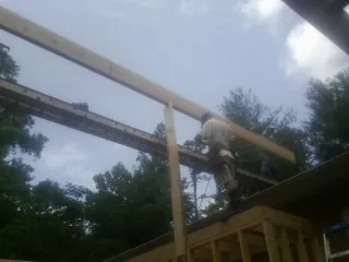 Carpenter setting a ridge beam over a new addition frame — Ice Dam Removal by Roofing Brothers in Fultondale