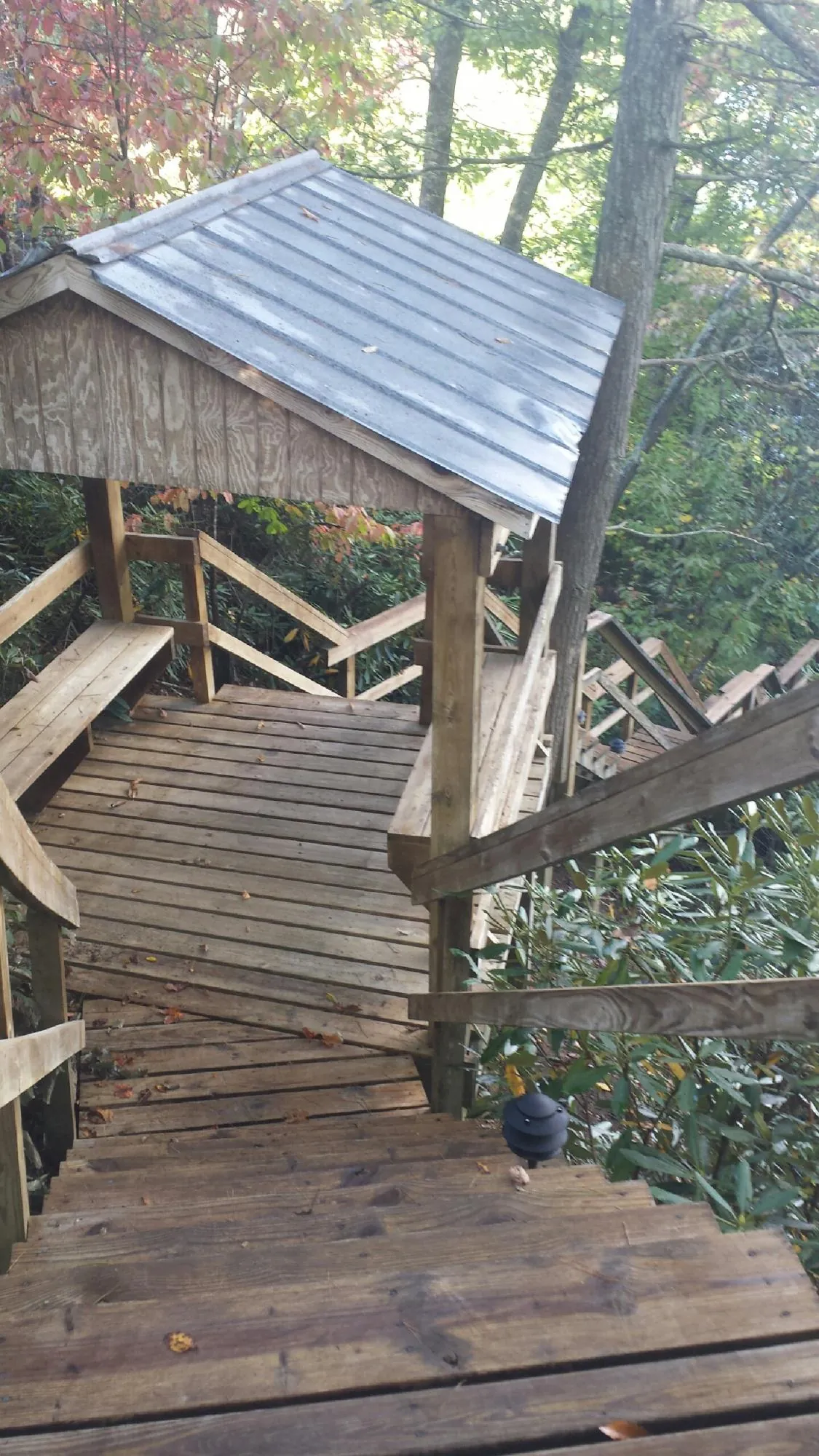 Metal roofed shelter over wooden steps on a wooded walkway — Skylight Repair & Installation work by our crew in Fultondale