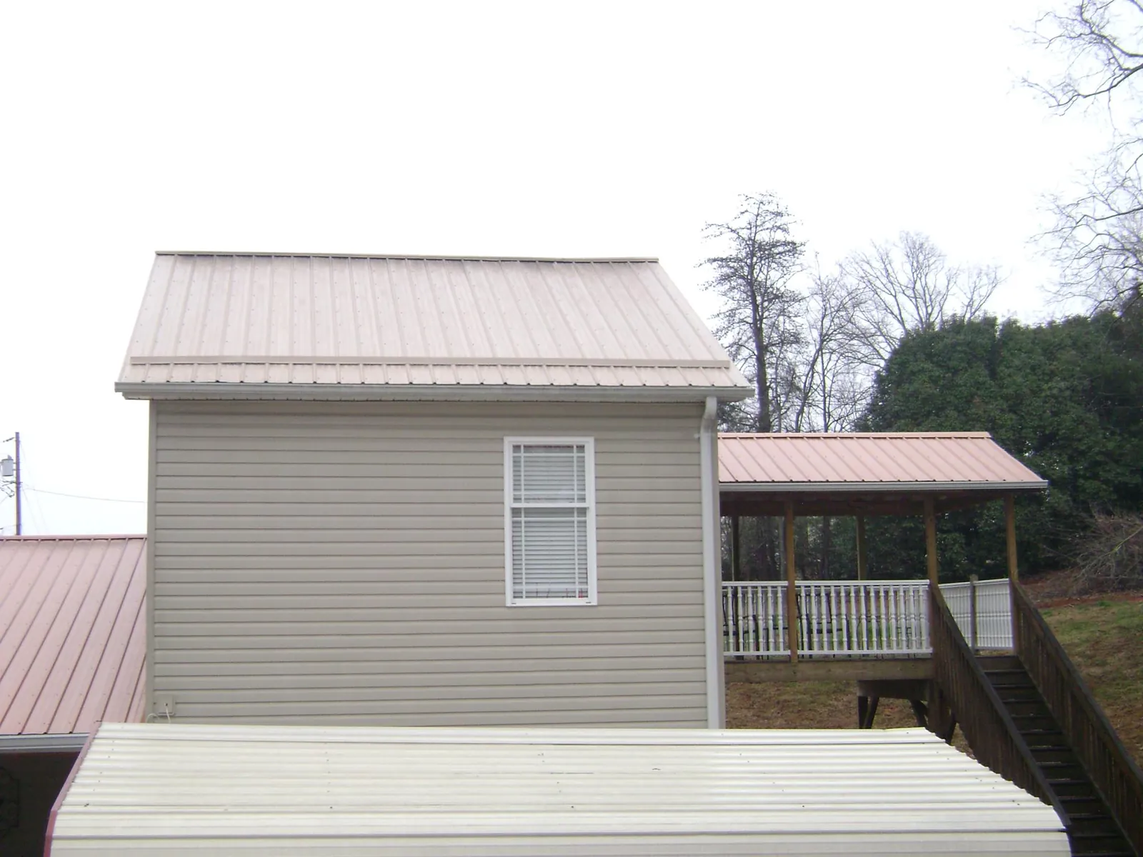 Tan metal roofs on a two story addition and attached porch, from a Roof Replacement job in Fultondale