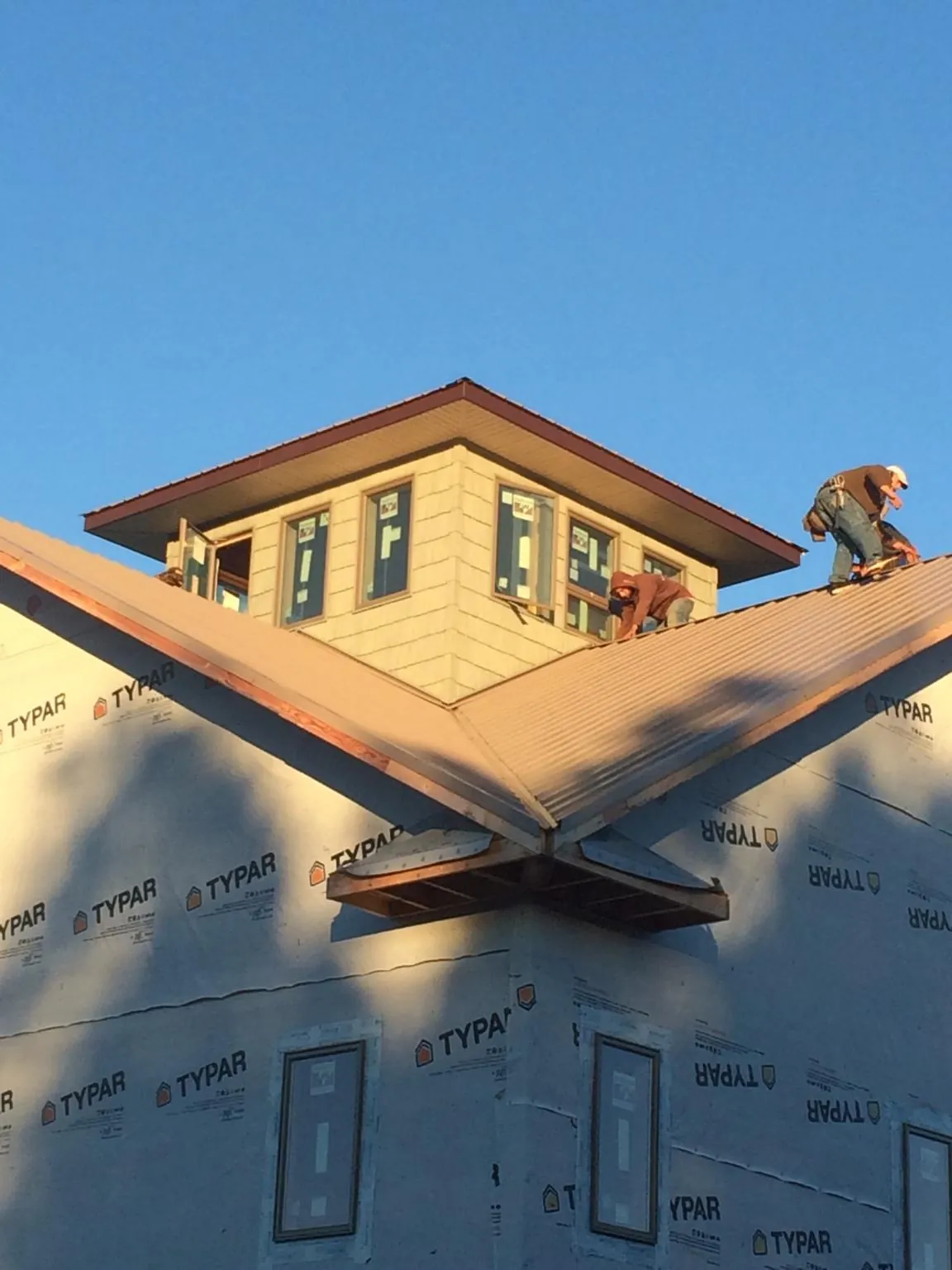 Roofers working around a rooftop cupola on a new metal roof at sunset — Roof Waterproofing in Fultondale by Roofing Brothers